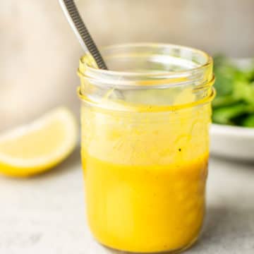 close-up of a mason jar with homemade honey mustard dressing and a spoon in it