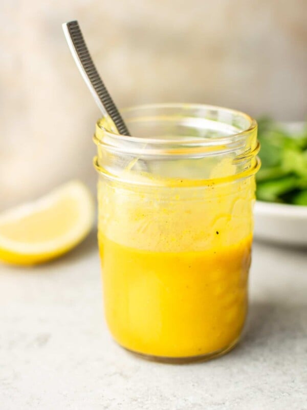 close-up of a mason jar with homemade honey mustard dressing and a spoon in it