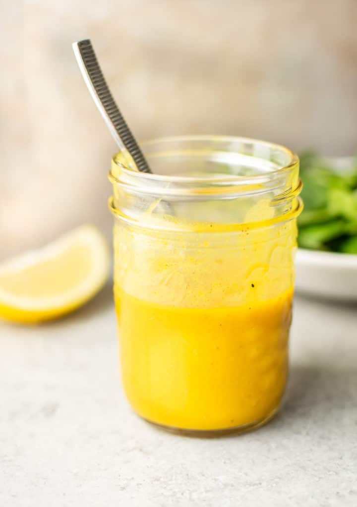 close-up of a mason jar with homemade honey mustard dressing and a spoon in it