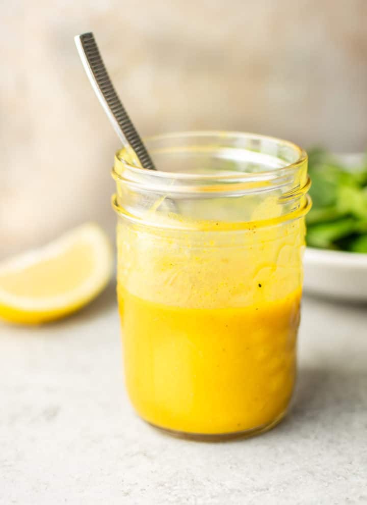 close-up of a mason jar with homemade honey mustard dressing and a spoon in it