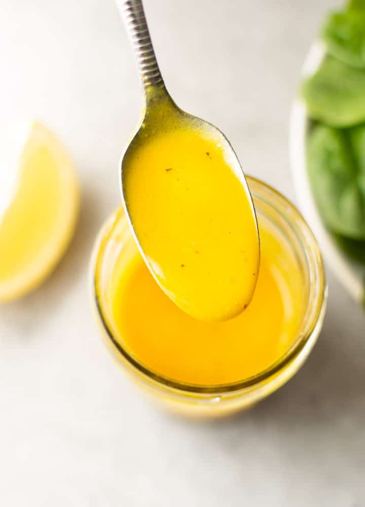 spoon being held above a mason jar of the BEST honey mustard dressing
