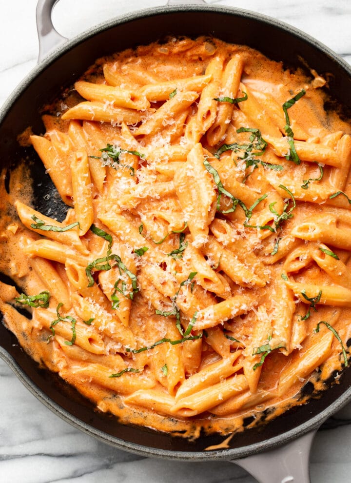 a cast iron skillet with penne alla vodka and grated parmesan