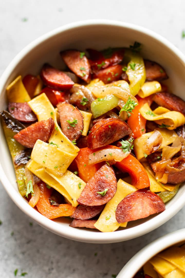 bowl of sausage peppers and onions served with egg noodles