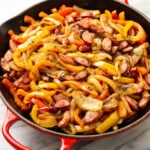 a cast iron skillet with sausage and peppers