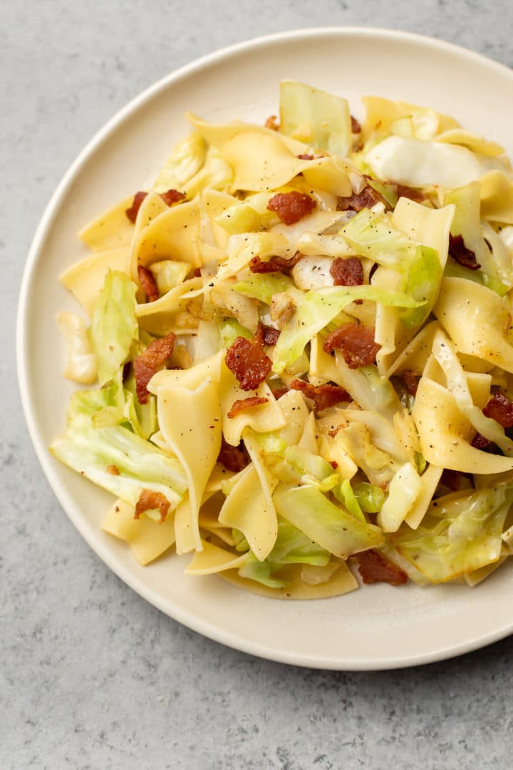 close-up of cabbage and noodles with bacon (on a beige plate)