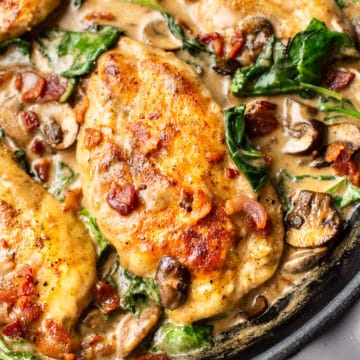 close-up of creamy balsamic bacon mushroom spinach chicken in a skillet
