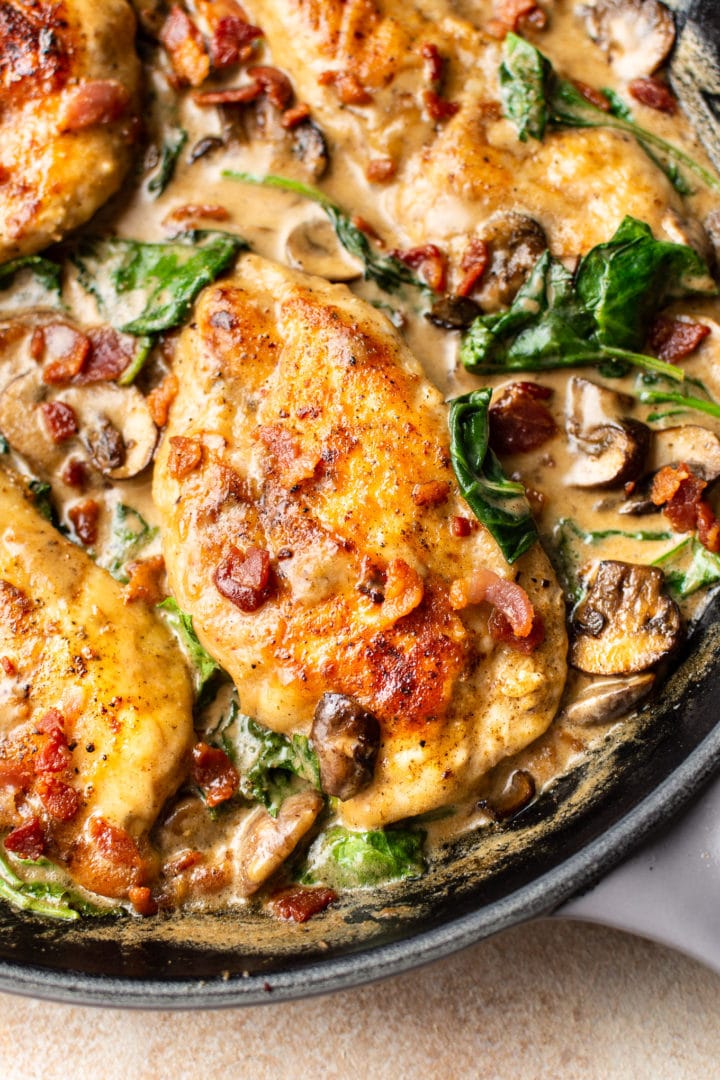 close-up of creamy balsamic bacon mushroom spinach chicken in a skillet