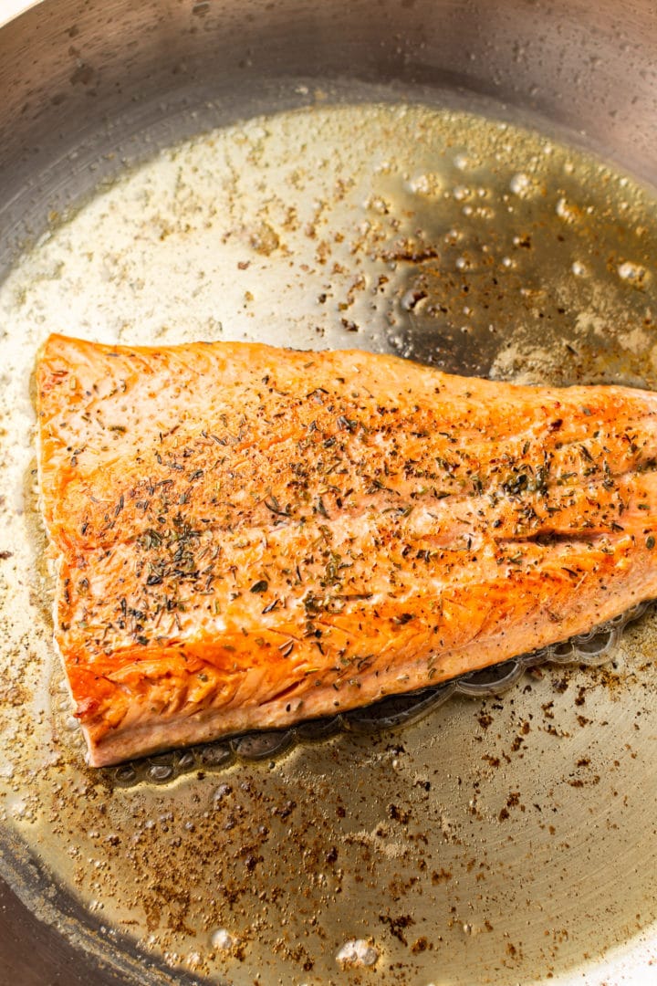 salmon being seared in a skillet for asparagus and salmon pasta