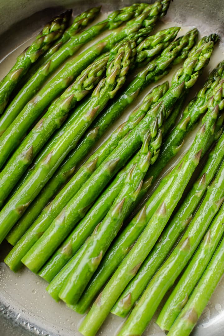 close-up (in a stainless steel pan) of easy poached asparagus