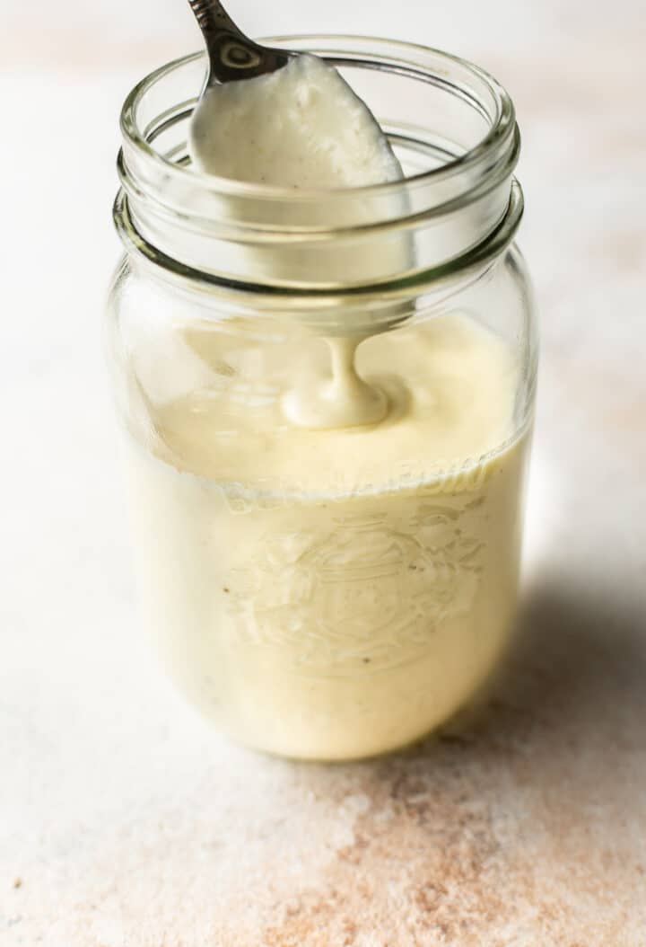 a glass jar with alfredo sauce and a spoon
