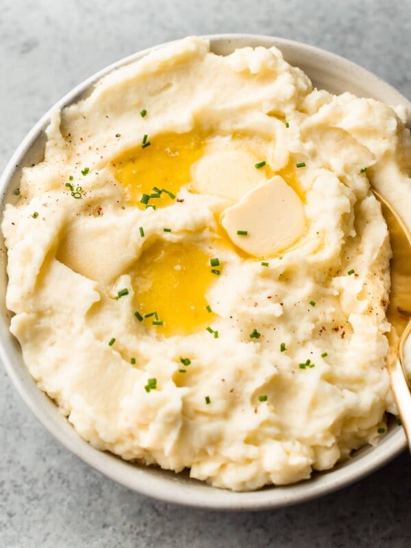 the best garlic mashed potatoes in a beige bowl with plenty of butter on top!