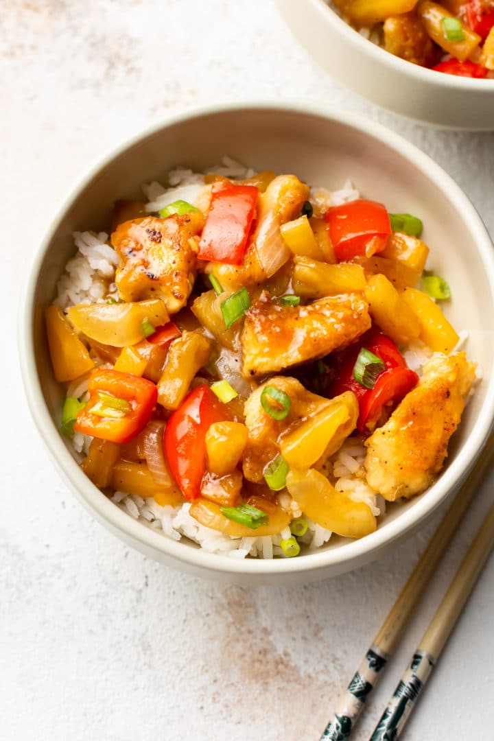 pineapple chicken on rice in a beige bowl