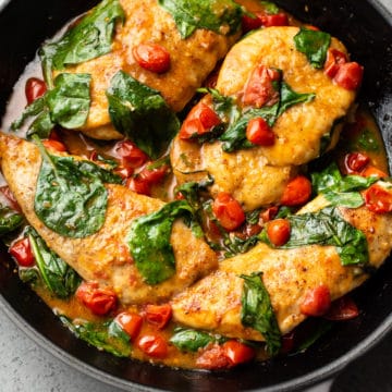 chicken breasts with a white wine, fresh tomato, and spinach sauce in a Le Creuset skillet