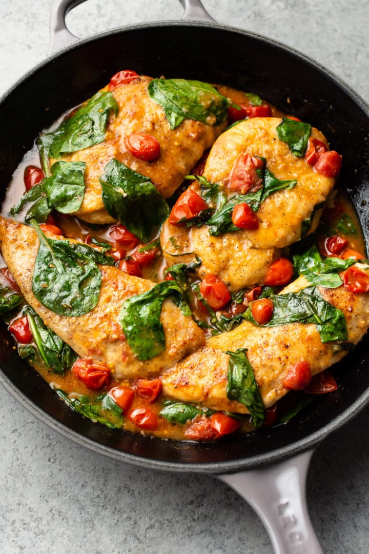 chicken breasts with a white wine, fresh tomato, and spinach sauce in a Le Creuset skillet