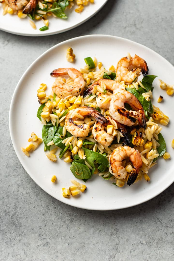 Cajun grilled shrimp and orzo salad on two white plates