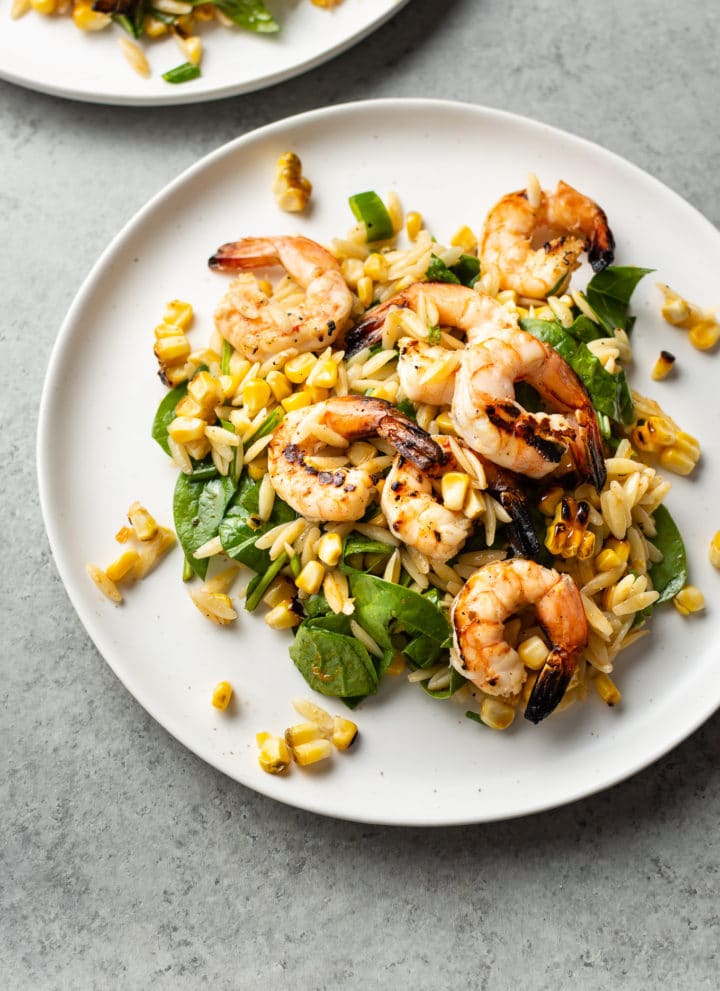 Cajun grilled shrimp and orzo salad on two white plates