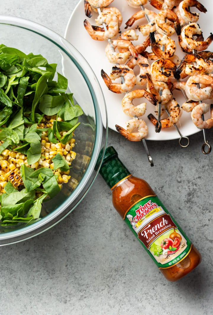 cooked shrimp skewers on plate, salad in prep bowl, and Tony Chachere's French dressing