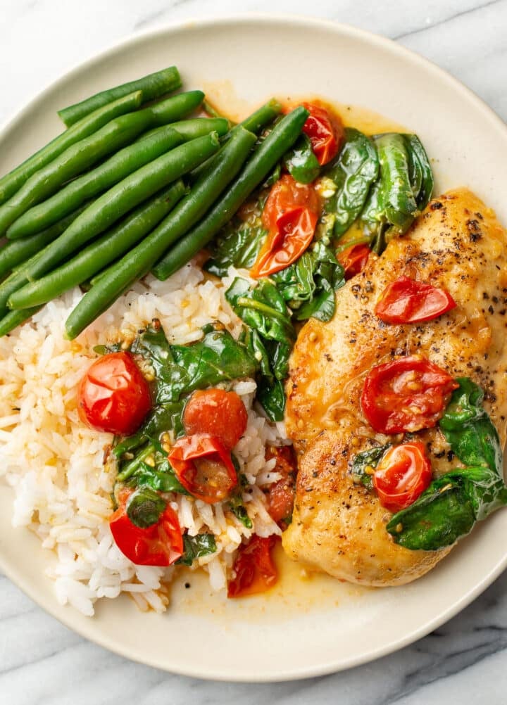 a plate with spinach, green beans, and rice with white wine tomato chicken