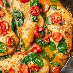 a cast iron skillet with tomato spinach white wine chicken