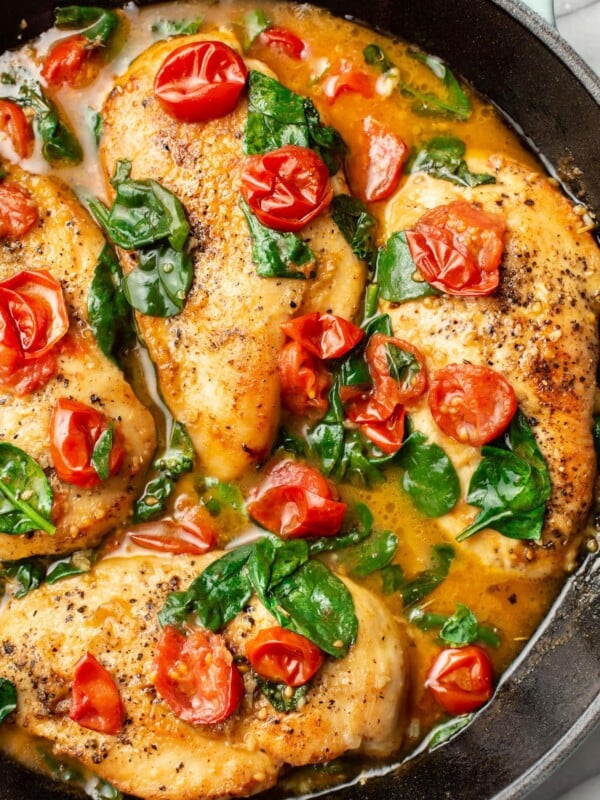 a cast iron skillet with tomato spinach white wine chicken