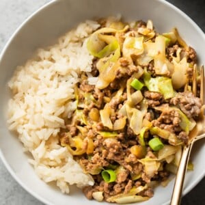 close-up of beef and cabbage stir fry with rice in a white bowl