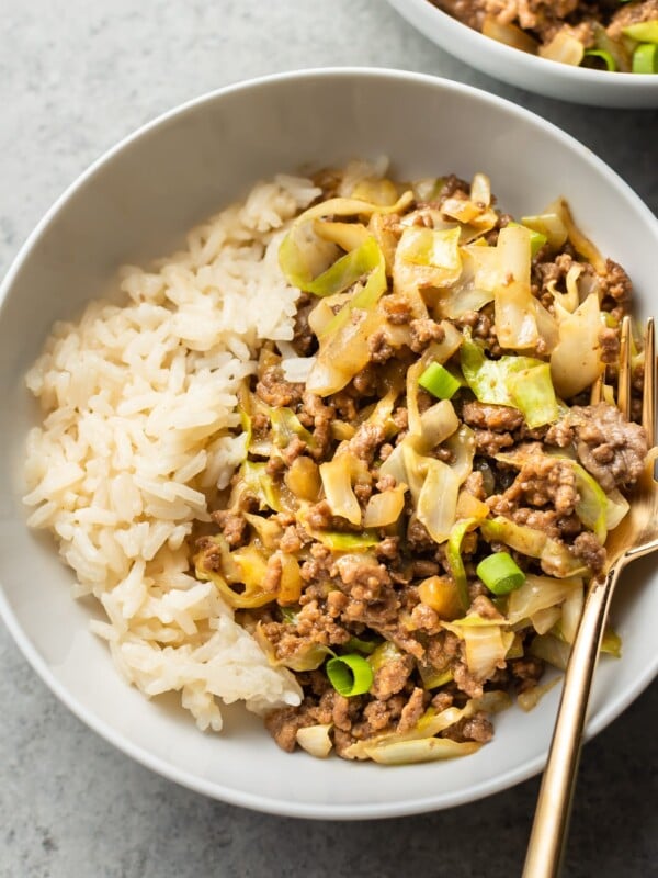 close-up of beef and cabbage stir fry with rice in a white bowl