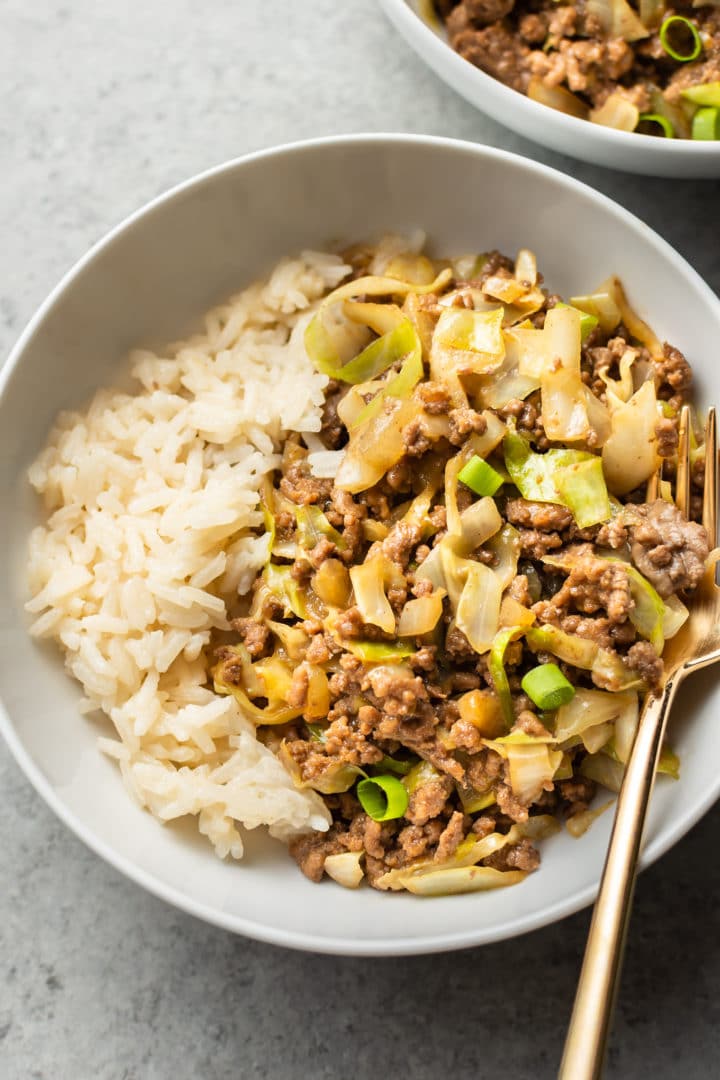 close-up of beef and cabbage stir fry with rice in a white bowl