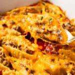 close-up of a beef stuffed shell being lifted out the baking dish