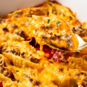 close-up of a beef stuffed shell being lifted out the baking dish