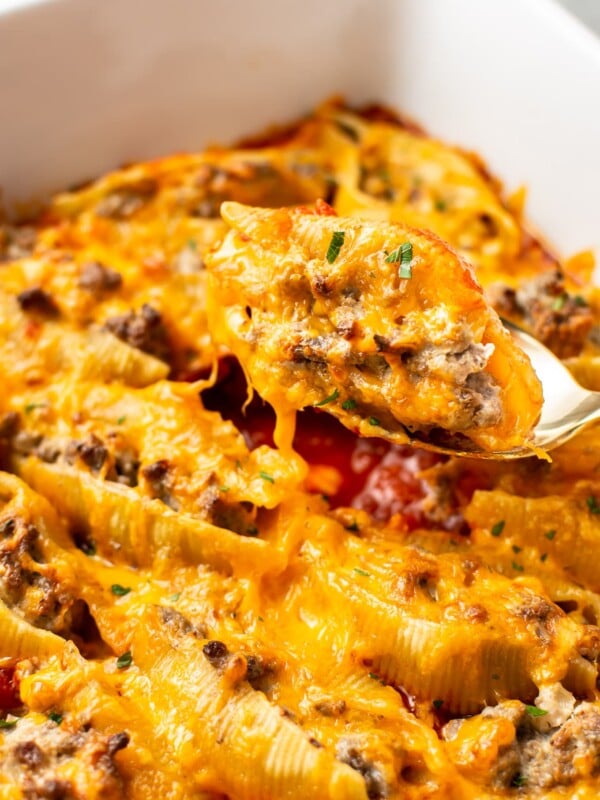 close-up of a beef stuffed shell being lifted out the baking dish