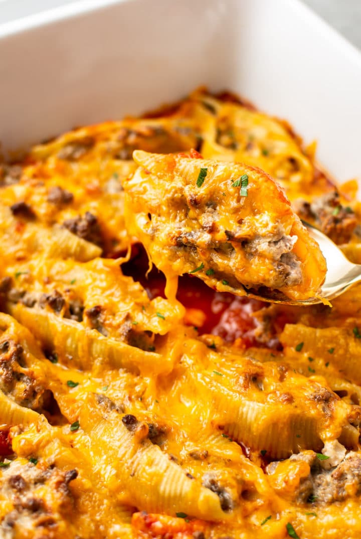 close-up of a beef stuffed shell being lifted out the baking dish