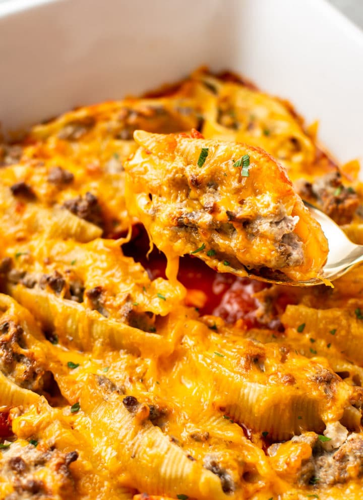 close-up of a beef stuffed shell being lifted out the baking dish