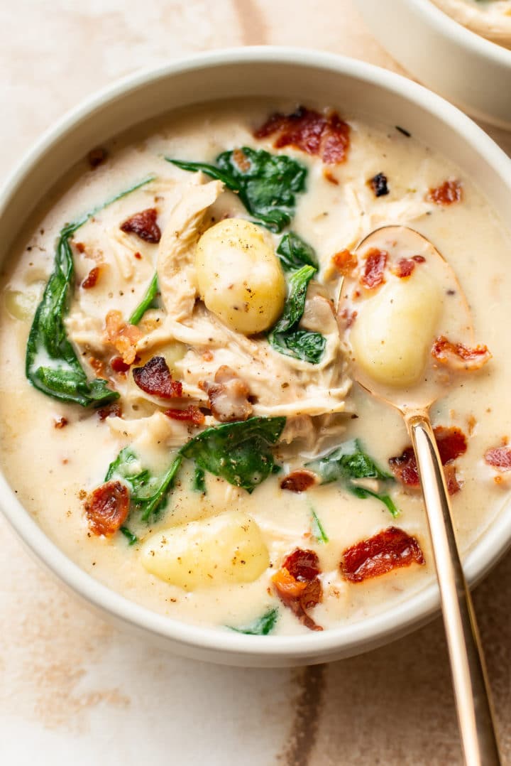 close-up of chicken bacon gnocchi soup in a bowl with a gold spoon