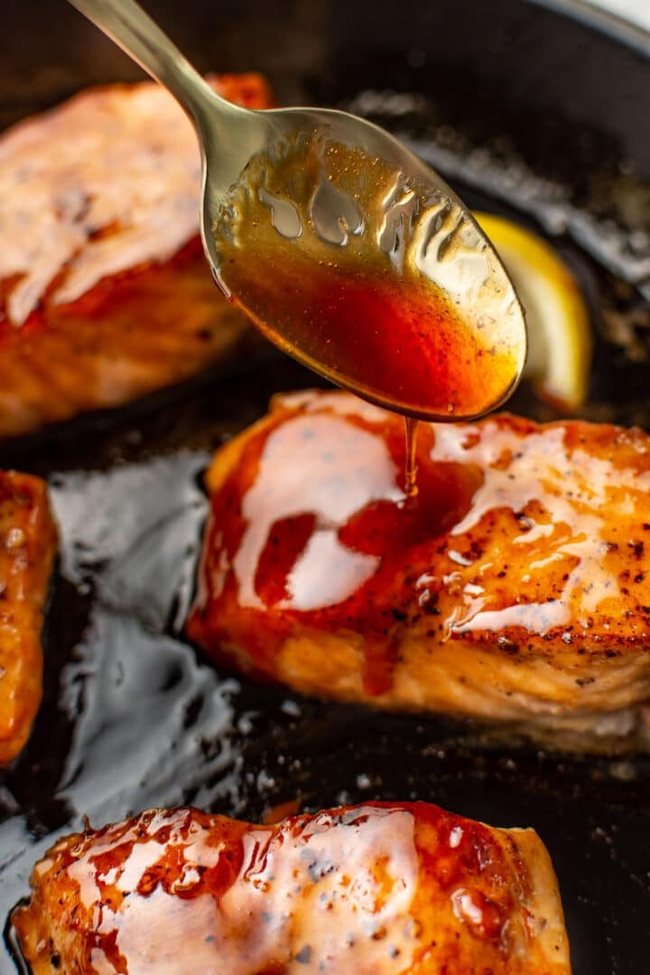 spooning honey garlic sauce on a piece of salmon
