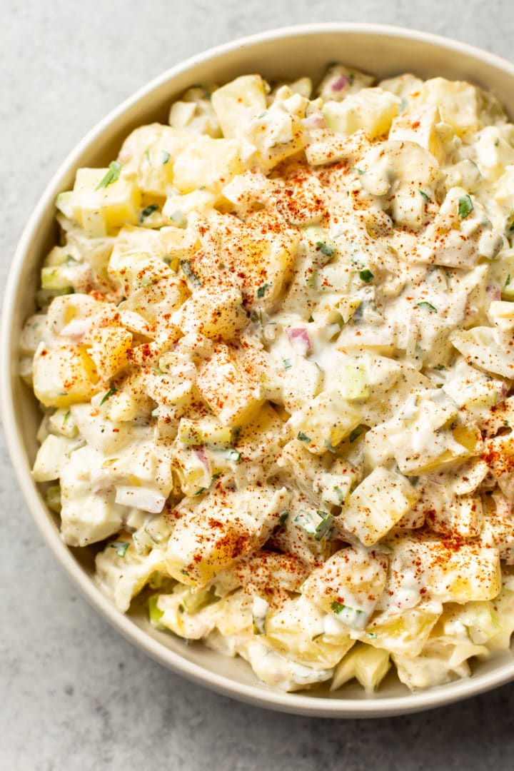 classic potato salad with egg in a beige serving bowl