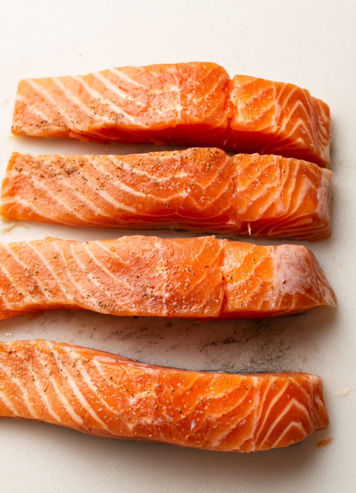 uncooked salmon on a board cut into 4 equal pieces