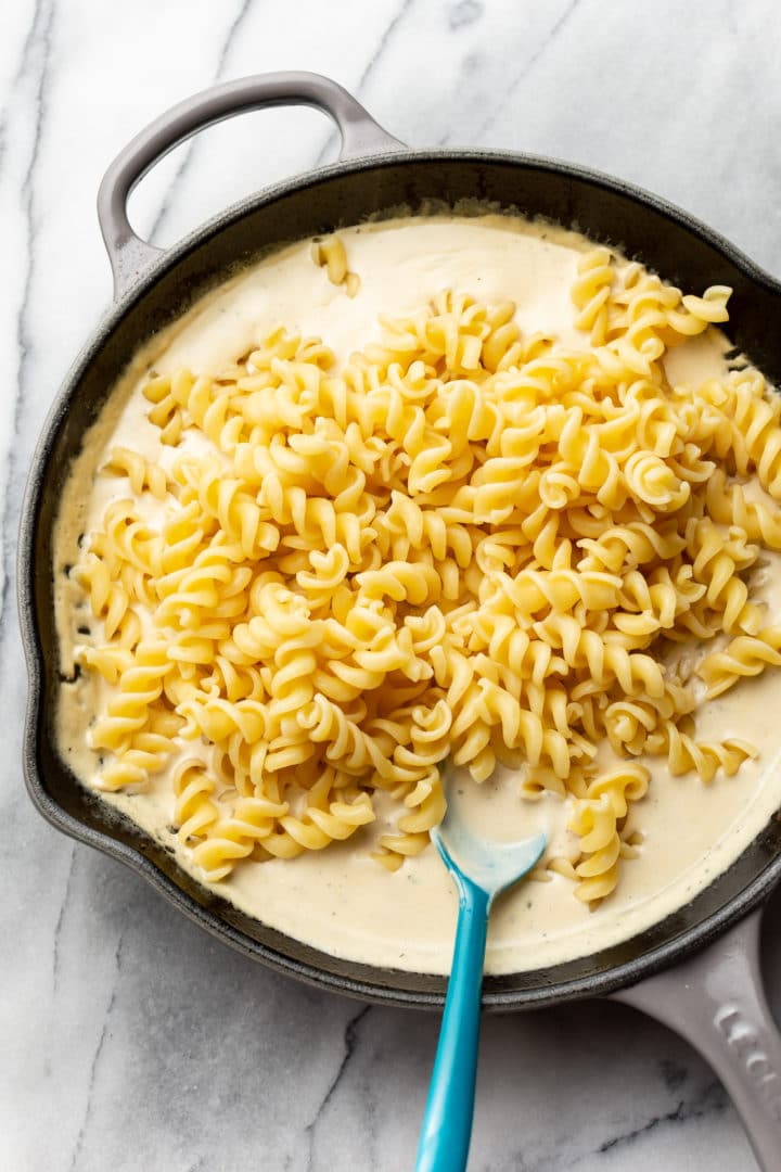 pasta being tossed with the creamy ranch sauce (in a skillet)