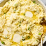 close-up of cream cheese mashed potatoes in a serving bowl with a gold spoon