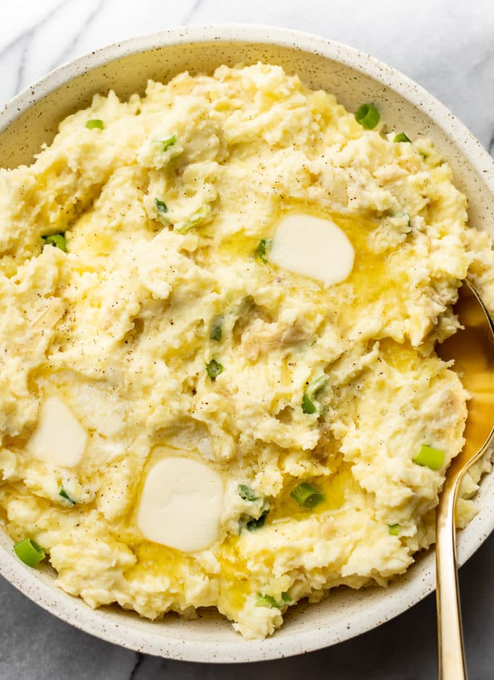 close-up of cream cheese mashed potatoes in a serving bowl with a gold spoon