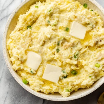 the best cream cheese mashed potatoes in a serving bowl with pats of butter on top