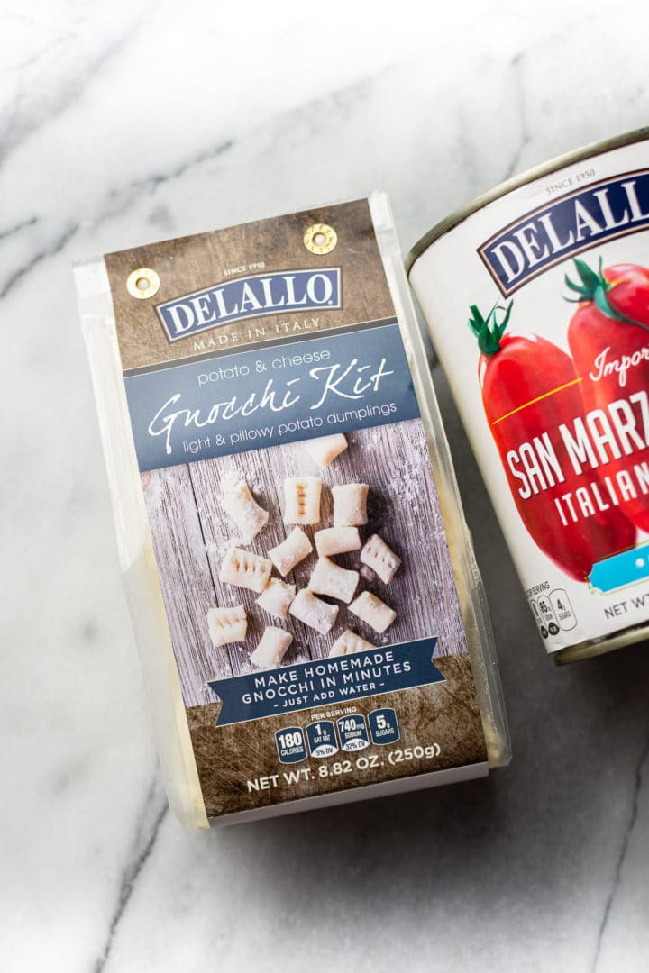 DeLallo's gnocchi kit & a 28 ounce can of DeLallo's San Marzano style crushed tomatoes on a marble background