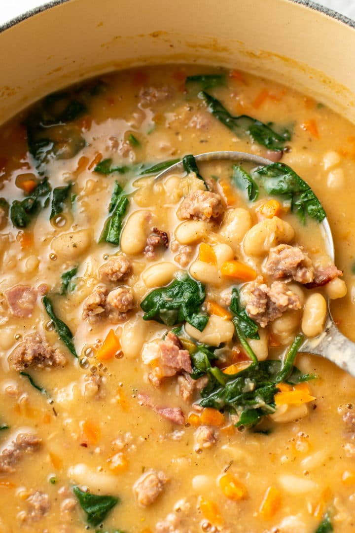 close-up of Italian sausage white bean soup in a pot with ladle