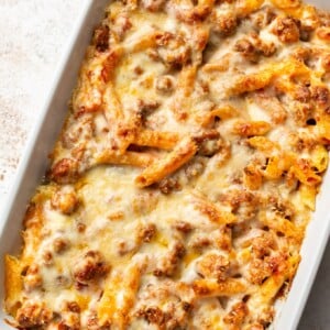 penne pasta bake with sausage in a white 9x13 baking dish