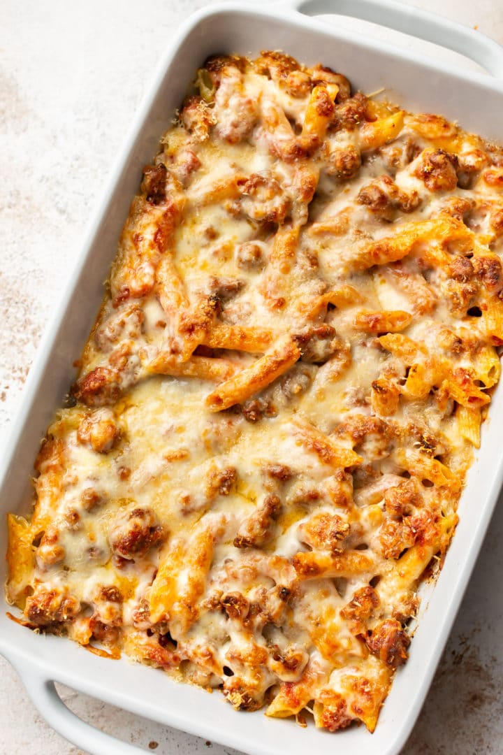 penne pasta bake with sausage in a white 9x13 baking dish