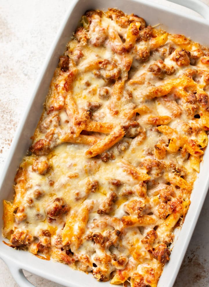 penne pasta bake with sausage in a white 9x13 baking dish