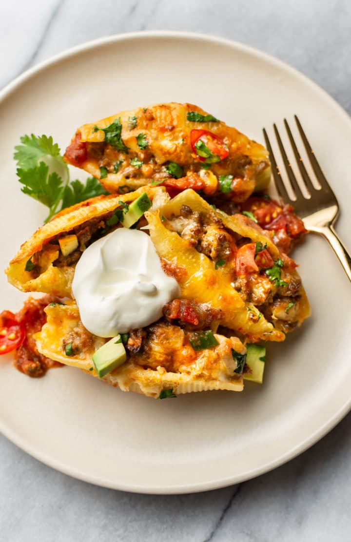 taco stuffed jumbo shells on a plate with a dollop of sour cream on top
