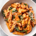 creamy tomato spinach chicken pasta in a white bowl