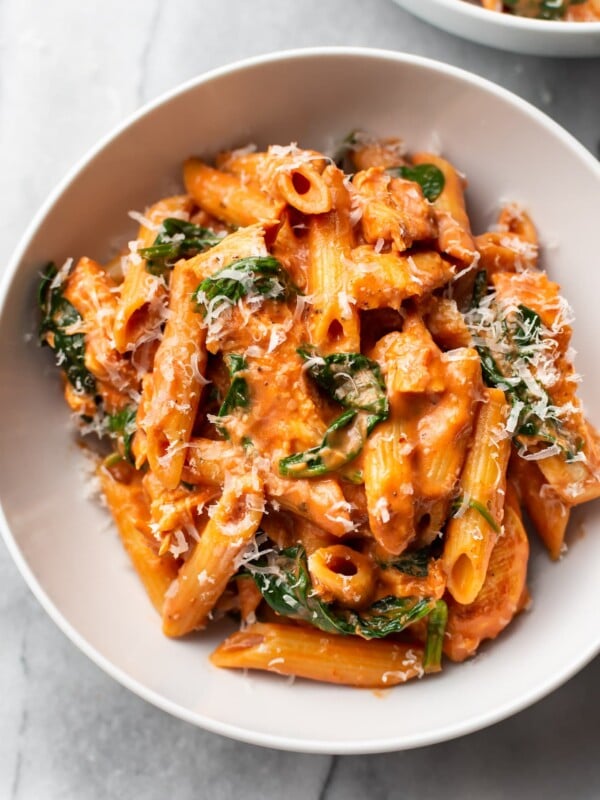 creamy tomato spinach chicken pasta in a white bowl