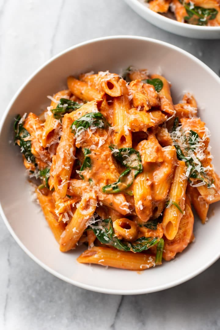 creamy tomato spinach chicken pasta in a white bowl