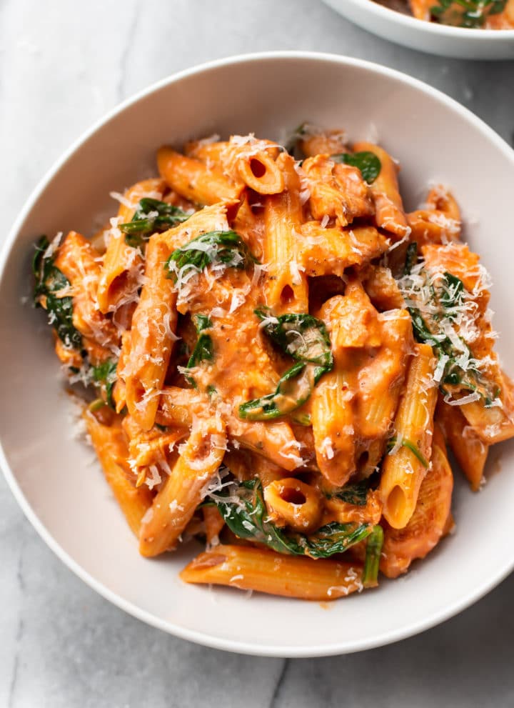 creamy tomato spinach chicken pasta in a white bowl